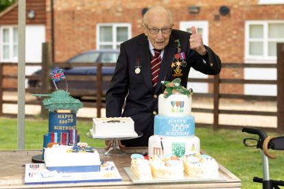A handout picture released on April 30, 2020 shows Captain Tom Moore posing for a photograph with cakes to celebrate his 100th birthday in Marston Moretaine, north of London. (Photo by Emma SOHL / CAPTURE THE LIGHT / AFP) / RESTRICTED TO EDITORIAL USE - MANDATORY CREDIT "AFP PHOTO / CAPTURE THE LIGHT / EMMA SOHL" - NO MARKETING NO ADVERTISING CAMPAIGNS - DISTRIBUTED AS A SERVICE TO CLIENTS --- NO ARCHIVE ---