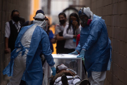 Un hombre de 20 años que se desmayó es conducido con todas las medidas de bioseguridad a una ambulancia este martes a las afueras de un centro comercial en Morelia, estado de Michoacán. EFE/ Iván Villanueva