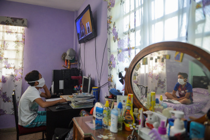Children watch a class on TV at their home in Havana, on April 23, 2020. - All schools were closed in Cuba due to the COVID-19 pandemic, something unprecedented in 60 years, not even when the strongest hurricanes hit the island. But Cubans had an ace under the sleeve: the teleclass. (Photo by YAMIL LAGE / AFP)