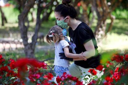 Una mujer deja un beso en la frente de su hija en un parque en Córdoba, sur de España.