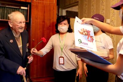 El veterano de la Segunda Guerra Mundial, Ivan Nikolaevich Golikov (L) es recibido por los empleados de la empresa de comunicaciones móviles Megacom para celebrar el Día de la Victoria en su casa en Bishkek, Kirguistán.