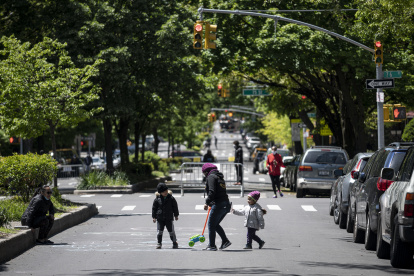 A woman plays with two children on a street, closed to vehicular traffic during a pilot program to provide more space for social distancing amid the novel coronavirus pandemic, on May 13, 2020 in Queens borough of New York City. (Photo by Johannes EISELE / AFP)