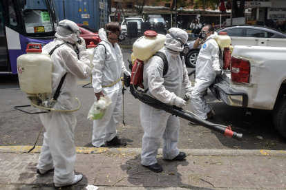 Cleaning workers wearing personal protective equipment (PPE) disinfect a street in Mexico City, on May 7, 2020, amid the new coronavirus pandemic. (Photo by PEDRO PARDO / AFP)