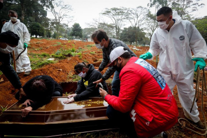 James Ala, coordinador de sepultureros, observa una familia desconsolada durante el entierro de un ser querido en el cementerio Vila Formosa, en Sao Paulo (Brasil).