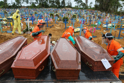 Los ataúdes se descargan para ser enterrados en una fosa común en el cementerio Nossa Senhora en Manaos, estado de Amazon, Brasil, el 6 de mayo de 2020. (Foto de MICHAEL DANTAS / AFP)