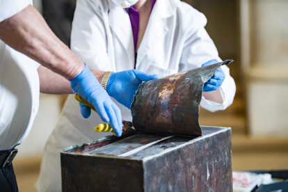 Ralph Coppage (izquierda), líder mecánico de mantenimiento, y Caitlin Smith (derecha), conservadora, trabajan para abrir la caja de recuerdos del Anfiteatro Memorial en la Capilla Inferior del Anfiteatro Memorial en el Cementerio Nacional de Arlington, Arlington, Virginia, Estados Unidos.
