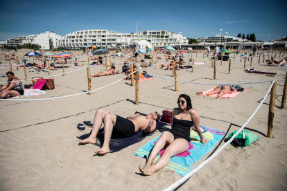 LA GRANDE MOTTE (Francia). Dos personas toman el sol en una playa en el sur de Francia. El municipio local es el primero en implementar zonas separadas para respetar el distanciamiento social.
