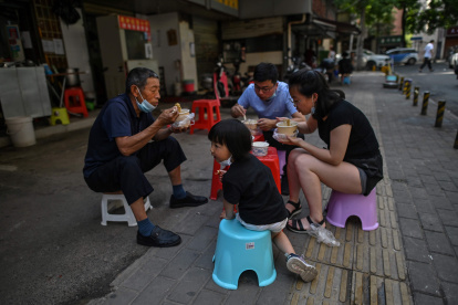 WUHAN. Una familia come en grupo y al aire libre en un restaurante callejero. Esta ciudad china vive ya varios días de una fase de pospandemia.