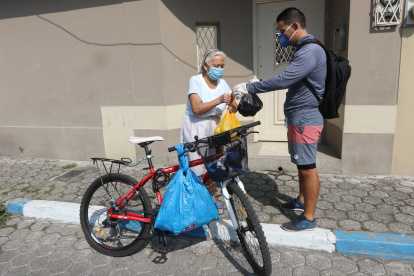 Enrique Bravo entrega el mandado a una de sus vecinas de la tercera edad, en Samanes. Él, para movilizarse, utiliza una bicicleta, así puede salir a ayudar todos los días.