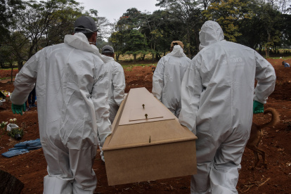 Employees carry the coffin of a person who died from COVID-19 at the Vila Formosa cemetery, in the outskirts of Sao Paulo, Brazil on May 20, 2020. - Brazil has emerged as the latest flashpoint in the coronavirus pandemic. The country has registered more than 270,000 cases and nearly 18,000 deaths so far, and the increase in infections is not expected to peak until June. (Photo by NELSON ALMEIDA / AFP)