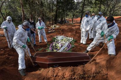 Employees bury the coffin of a person who died from COVID-19 at the Vila Formosa cemetery, in the outskirts of Sao Paulo, Brazil on May 20, 2020. - Brazil has emerged as the latest flashpoint in the coronavirus pandemic. The country has registered more than 270,000 cases and nearly 18,000 deaths so far, and the increase in infections is not expected to peak until June. (Photo by NELSON ALMEIDA / AFP)