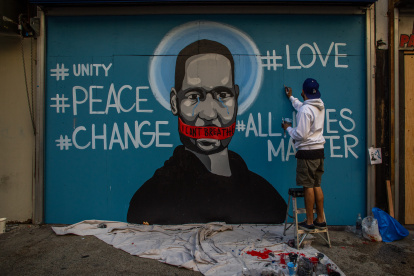 The artist Celos paints a mural in Downtown Los Angeles on May 30, 2020 in protest against the death of George Floyd, an unarmed black man who died while while being arrested and pinned to the ground by the knee of a Minneapolis police officer. - Clashes broke out and major cities imposed curfews as America began another night of unrest Saturday with angry demonstrators ignoring warnings from President Donald Trump that his government would stop violent protests over police brutality "cold." (Photo by Apu GOMES / AFP) / RESTRICTED TO EDITORIAL USE - MANDATORY MENTION OF THE ARTIST UPON PUBLICATION - TO ILLUSTRATE THE EVENT AS SPECIFIED IN THE CAPTION
