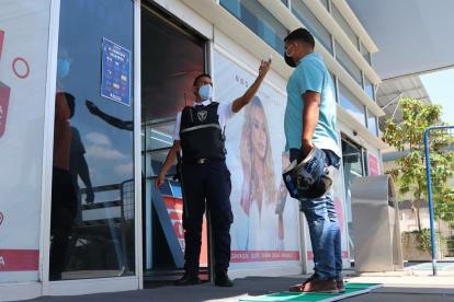 Un guardia de la Terminal Terrestre de Guayaquil toma la temperatura a un ciudadano.