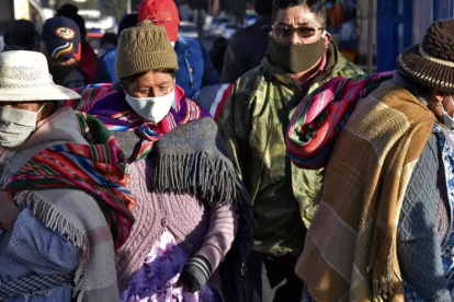 Personas que llevan máscaras faciales caminan por las calles de El Alto mientras Bolivia busca reactivar la economía en medio de la nueva pandemia de coronavirus.