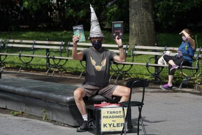 El mago de los juegos y las cartas del tarot, Kyler James, se sienta en el Washington Square Park de Nueva York el 9 de junio de 2020. ¿Cuándo podría haber una vacuna?