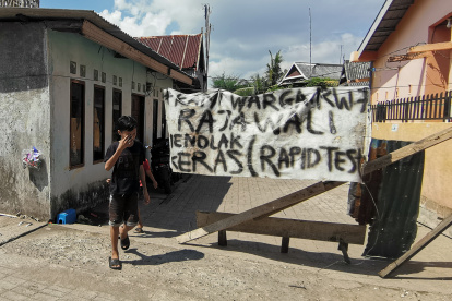 En esta imagen tomada el 8 de junio de 2020, un aldeano de pie junto a una pancarta lee su rechazo a la prueba rápida para los miembros de su comunidad en medio de la preocupación por el coronavirus COVID-19, en Makassar, South Sulawesi. Decenas de indonesios han sido arrestados por arrebatar a las víctimas de COVID-19 de los hospitales en un intento por enterrarlos de acuerdo con las costumbres locales en la nación de mayoría musulmana, dijo la policía.