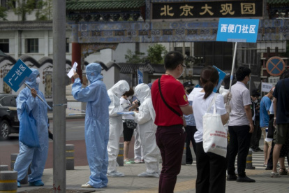Miembros del personal sanitario sostienen carteles con indicaciones en el mercado de Xinfadi.