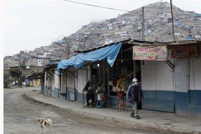 Un hombre con mascarilla camina frente a un puesto de venta de arreglos florales en las inmediaciones del Cementerio de Nueva Esperanza del distrito de Villa María del Triunfo, una de las zonas más populosas de Lima, capital de Perú.