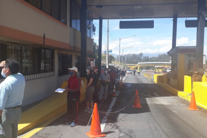 Usuarios esperan encolumnados por un turno de atención en elsector del peaje de la avenida Rumiñahui, de Quito.