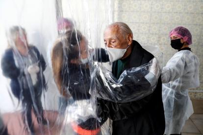 SAO PAULO. María Paula Moraes saluda a su padre Wanderley de 82 años, que vive en una residencia de ancianos, a través de una "cortina de abrazos", una alternativa válida para amenizar las medidas de distanciamiento social, durante el avance de la pandemia del coronavirus en Brasil.
