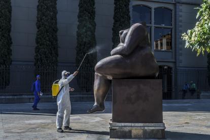 Un trabajador desinfecta una estatua de los artistas colombianos Fernando Botero, en Medellín, en medio de la pandemia de Covid-19