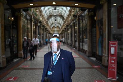 LEED. Un guardia de un área comercial de esta ciudad inglesa, se protege todo el rostro, mientras Inglaterra se prepara para hacer obligatorio el uso de cubiertas faciales en las tiendas.