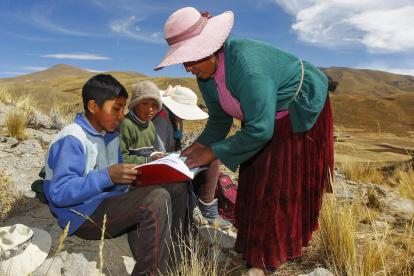 Raymunda Charca (R) helps her children (L-R) Juan Carlos, 13, Alvaro, 10, and Roxana Cabrera, 16, on top of a hill where they can pick up signal on their mobile phones to receive virtual classes during the COVID-19 novel coronavirus pandemic, near their house in the remote highland community of Conaviri, district of Manazo, in the Peruvian Andes close to Lake Titicaca and the border with Bolivia, early July 24, 2020. - As schools remain closed due to the pandemic, the Cabrera children participate in the "Learn at Home" educational platform which was implemented by the Peruvian Ministry of Education. (Photo by Carlos MAMANI / AFP)