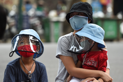 A woman waits with her children at a makeshift rapid testing centre as Vietnam records a rise in cases of the COVID-19 coronavirus in Hanoi on July 31, 2020. - Vietnam has recorded 45 news cases of COVID-19 -- its highest single daily tally since the pandemic began -- as an outbreak in the resort city of Danang erodes the country"s efforts to stay virus-free. (Photo by Nhac NGUYEN / AFP)