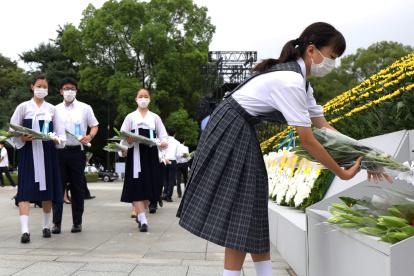 Jóvenes depositan ofrendas florales en honor a los fallecidos de la bomba de Hiroshima en el Parque de la Paz de la ciudad.