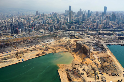 An aerial view taken on August 7, 2020, shows a partial view of the port of Beirut and the crater caused by the colossal explosion three days earlier of a huge pile of ammonium nitrate that had languished for years in a port warehouse, left scores of people dead or injured and caused devastation in the Lebanese capital. The city of Beirut can be seen in the background. (Photo by - / AFP)