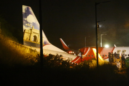 First responders inspect the wreckage of an Air India Express jet, which was carrying more than 190 passengers and crew from Dubai, after it crashed by overshooting the runway at Calicut International Airport in Karipur, Kerala, on August 7, 2020. - At least 14 people died and 15 others were critically injured when a passenger jet skidded off the runway after landing in heavy rain in India, police said on August 7. (Photo by Favas JALLA / AFP)