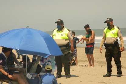 Dos agentes de policía desalojan a unos turistas que disfrutaban del balneario de Playas.