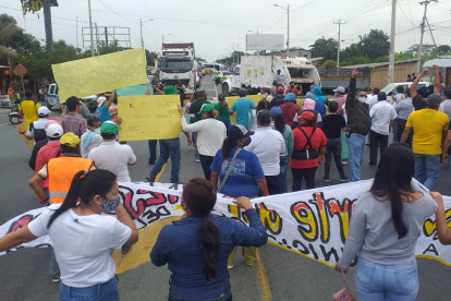 Con pancartas alusivas a sus reclamos, los funcionarios y trabajadores de los GADs bloquearon la carretera, este miércoles 13 de agosto de 2020.