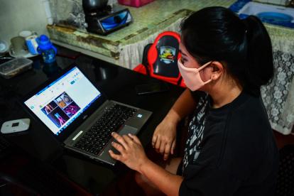 This photo taken on August 11, 2020 shows Lorraine Ann Imperio browsing her computer as she prepares to barter goods online in Las Pinas City, suburban Manila. - Struggling to make ends meet, Lorraine Imperio swapped a pair of Nike slip-ons for a whole dressed chicken on an online bartering site, one of dozens that have sprouted during the Philippines" virus lockdowns. (Photo by Maria TAN / AFP) / To go with AFP story Philippines-health-virus-lifestyle, FOCUS by Cecil Morella