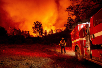 OROVILLE. Un bombero observa impasible cómo las llamas se elevan sobre su camión en el incendio en esta ciudad californiana la noche de este miércoles.