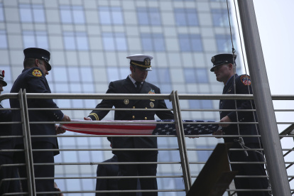 Bomberos se preparan para izar la bandera estadounidense en la conmemoración del año pasado.