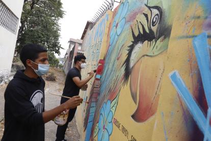 Los jóvenes vecinos pintan murales que bordean el Bosque Tropical.