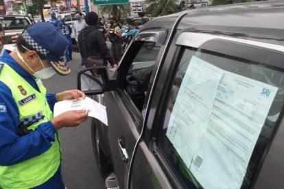 Un agente de la ATM lee un documento que le permite a un conductor circular.