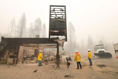 Shaver Lake. Bomberos recorren el lugar donde hasta inicios de semana estaba una tienda. Solo queda el letrero en pie, tras el paso del incendio.