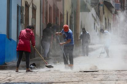 Habitantes barren la ceniza del volcán Sangay en una calle de Alausí, en la provincia de Chimborazo.