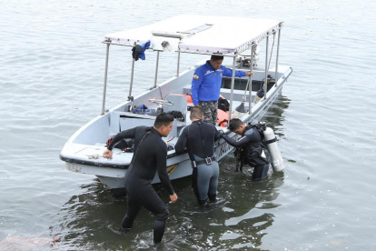 Buzos del Grupo de Intervención y Rescate (GIR), de la Policía Nacional, realizan la búsqueda del muchacho.
