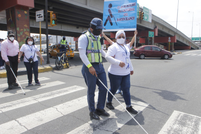 El agente de ATM, Miguel Saltos, se pone en el lugar de una persona con discapacidad al vendar sus ojos y cruzar la calle.