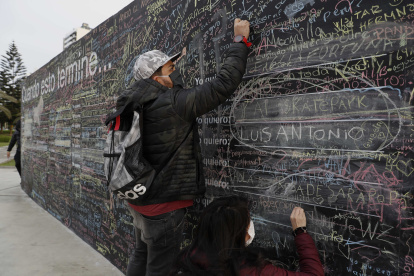 Una pareja escribe sus deseos post-pandemia en "El muro de la esperanza", en un parque del malecón de Lima.