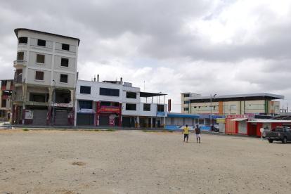 Moradores de Tarqui pasan por el terreno donde antes se ubicaba el mercado que se destruyó con el terremoto de 2016.