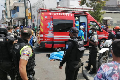 La víctima yace en el piso entre socorristas y policías que acudieron al lugar del crimen.