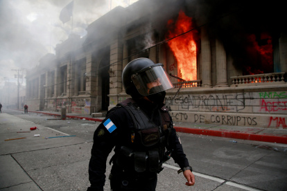 Un policía camina junto al fuego desatado, el 21 de noviembre de 2020, en el Congreso en Ciudad de Guatemala durante una jornada de protestas.