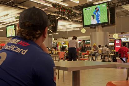 Steven Toledo trabaja en una empresa de envíos exprés. Aprovecha un tiempo libre para observar los partidos de Emelec.Lo hace en el patio de comidas de un centro comercial.