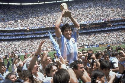 El argentino Diego Maradona en uno de los momentos cumbres de su carrera levantando el trofeo en el Mundial de México 86, gesta ecuménica donde además de marcar cinco goles, fue el cerebro de un conjunto albiceleste que celebró su segundo cetro a ese nivel.