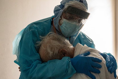 Médico abraza a paciente con covid, anciano, en cuidados intensivos.