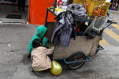 Fotografía de archivo donde se observan niños que acompañan a sus padres a trabajar con una carreta de productos vegetales en una calle de Quito.